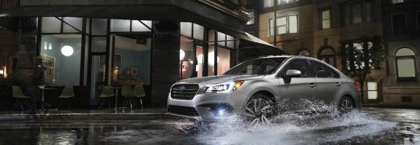 2019 Subaru Legacy in silver rounding a city corner with rain on the ground